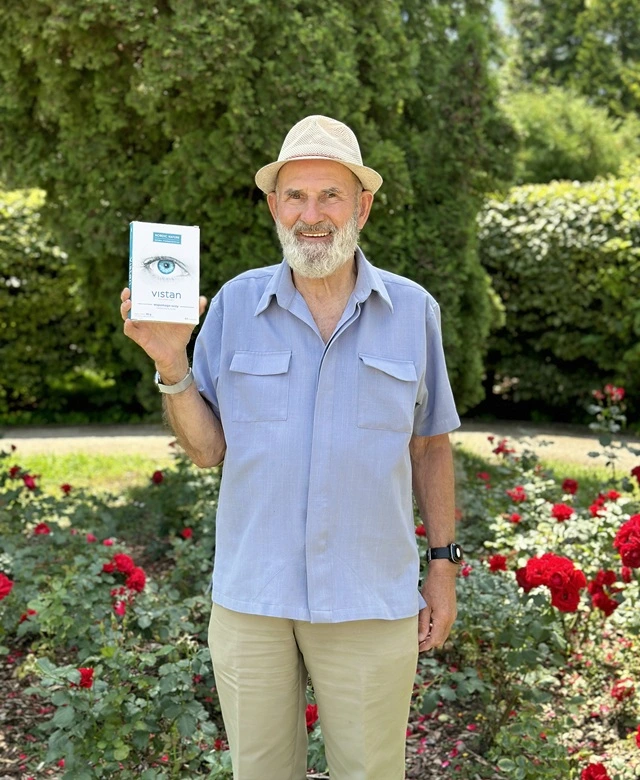 Natural Pharmaceuticals Vistan™ Rõõmsameelne vanem mees hoiab käes toidulisandi Vistan pakendit lilleaia taustal.